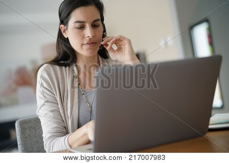 Home-office teleoperator talking on phone with headset