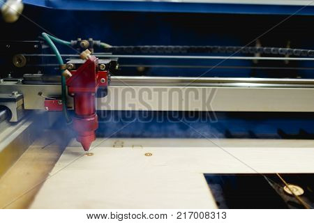 Automatic machine burns the laser wheel on the workpiece. There is smoke from work. Side view