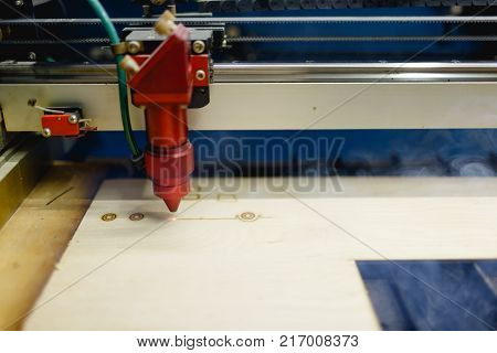 The automatic machine burns the bottom of the laser on the workpiece. There is a smoke from work. Side view