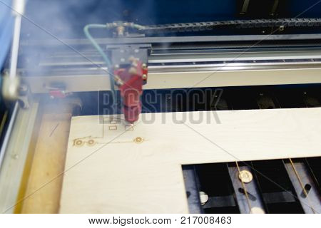 The automatic machine burns the truck cab on the workpiece with a laser. There is a smoke from work. Top view at an angle close up