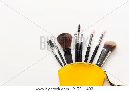 Makeup cosmetics tools background and beauty cosmetics products and facial cosmetics package lipstick eyeshadow in yellow bag on the white background. Lifestyle Concept.