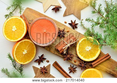 fresh oranges with anisestars, cinnamon sticks, juniper branches and aroma candle, Christmas time composition, top view