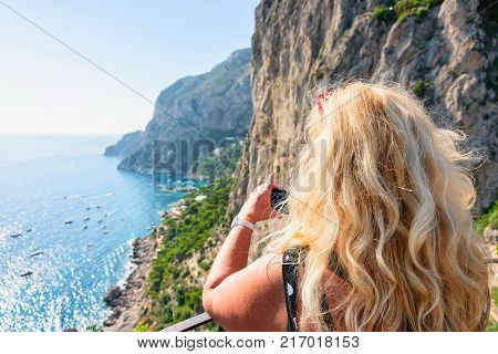 Woman taking photos of Marina Piccola on Capri Island Italy