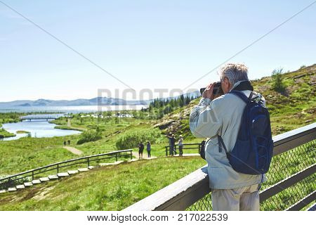 Aged tourist walking and photographing in national park Thingvellir in Iceland. excursion to the national park Thingvellir in Iceland