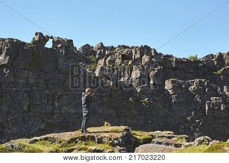 tourist walking and photographing in fracture of tectonic plates in national park Thingvellir in Iceland. excursion to the national park Thingvellir in Iceland