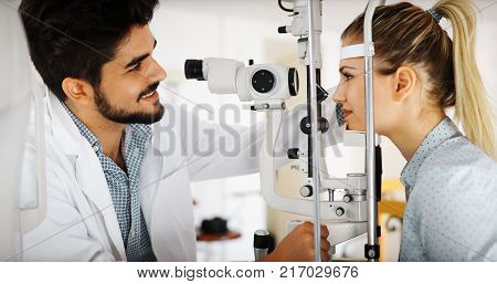 Optometrist examining patient in ophthalmology clinic with professional equipment