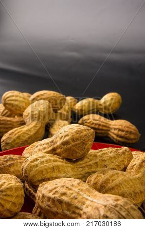 Peanuts, Arachis hypogaea, in shell on dark background, close up, selective focus