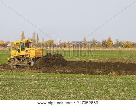 The Yellow Tractor With Attached Grederom Makes Ground Leveling.