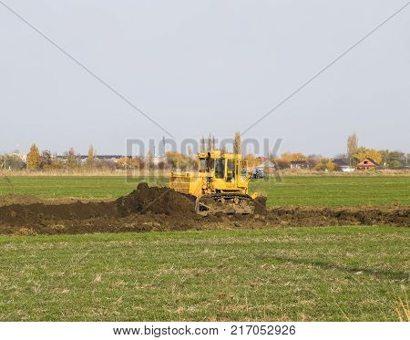 The Yellow Tractor With Attached Grederom Makes Ground Leveling.