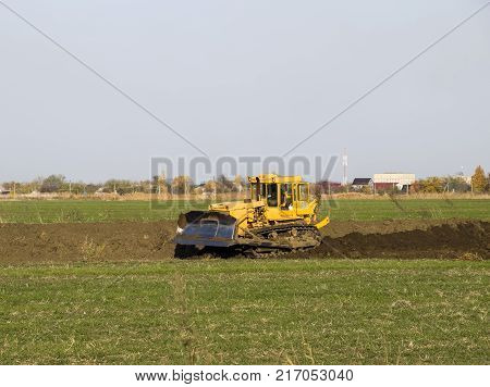 The Yellow Tractor With Attached Grederom Makes Ground Leveling.