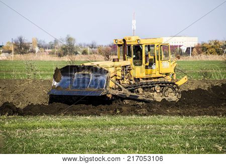 The Yellow Tractor With Attached Grederom Makes Ground Leveling.