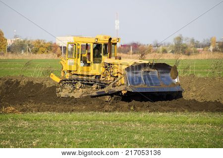 The Yellow Tractor With Attached Grederom Makes Ground Leveling.