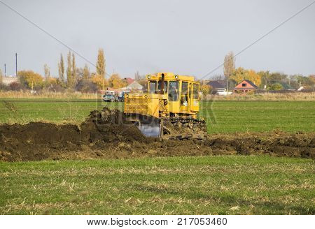 The Yellow Tractor With Attached Grederom Makes Ground Leveling.