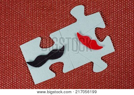 Close-up of 2 pieces of a puzzle. A symbolic man with a mustache and a woman with lips. The concept of psychological compatibility