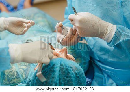 Male Old Professional Dentist Surgeon In Uniform And Female Assistant Helps To Performing Operation