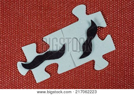Close-up of two parts of a puzzle. Symbolic men with a mustache. The concept of psychological compatibility, friendship.