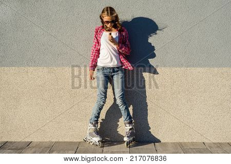A young  cool girl, shod in rollerblades holding and eating chocolate bar. Energy and enjoyment