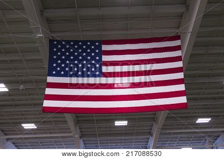 An large american flag hanging from the rafters of an indoor areana.