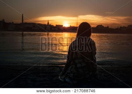 girl standing on the beach watching the sunset
