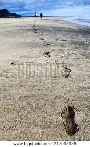 Close up of footprints in the sand on the beach. Two people walking on the beach.