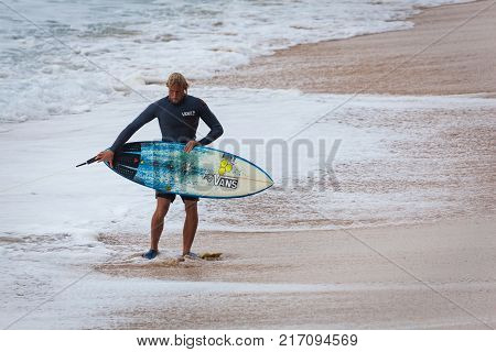 SUNSET BEACH HAWAII USA - DECEMBER 2, 2017: Competitive surfer with surfboard walking on beach at the 2017 Vans World Cup of Surfing competition at Sunset Beach on Oahu's scenic North Shore. This is the second of three surfing competitions and Conner Coff