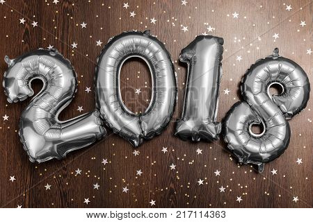 Bright silver balloons figures 2018, New Year Balloons with glitter stars on dark wood table background. Christmas and new year celebration