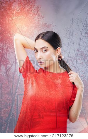 Satisfied client. Beautiful young fashionable woman being attentive while looking at her reflection in the mirror and feeling satisfied with the new haircut