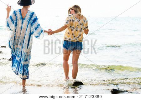 Girlfriends holding hands and walking on the beach