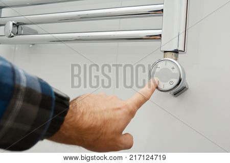 Man switch on electric towel rail radiator. Towel Radiator Heating Elements.Thermostatic Electric Towel Rail for Bathroom.