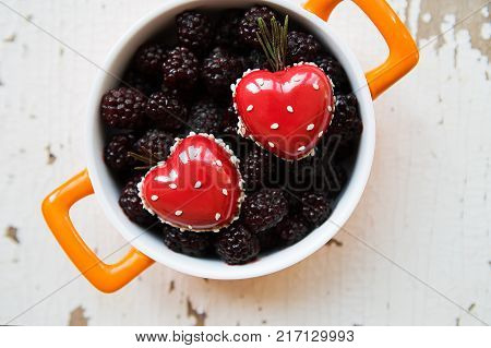 A full blackboy plate with a dessert in the form of a heart stands on a wooden background, close-up.