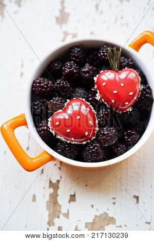 A full blackboy plate with a dessert in the form of a heart stands on a wooden background, close-up.