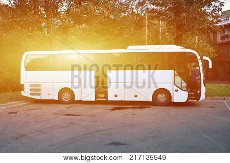 White tourist bus for excursions. The bus is parked in a parking lot near the park