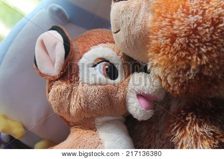 Bear and fawn toy sitting by the window in shadows