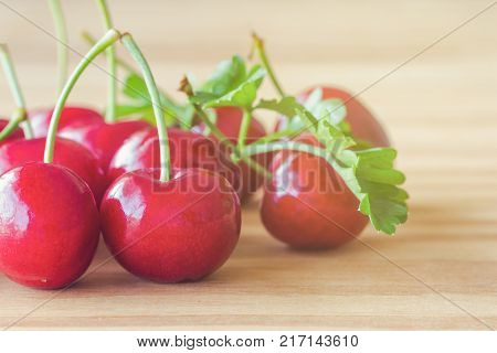 Close up fresh red cherries lay on rustic wood table. Red cherry in side view with copy space for background or wallpaper concept.. Cherry have high vitamin C and have sweet and sour taste. Red cherry is healthy and delicious fruit.