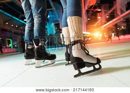 low section of couple in skates ice skating on rink