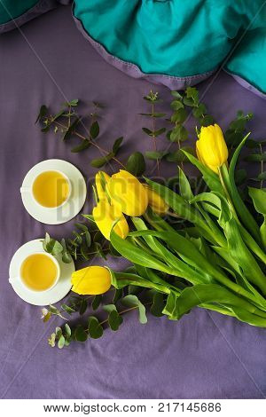 Yellow tulips and two cups of tea in bed, morning