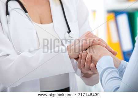 Hand of doctor reassuring her female patient. Medical ethics and trust concept