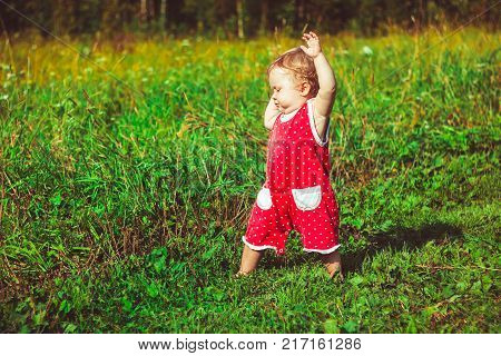 The child learns to walk in the park barefoot on the grass