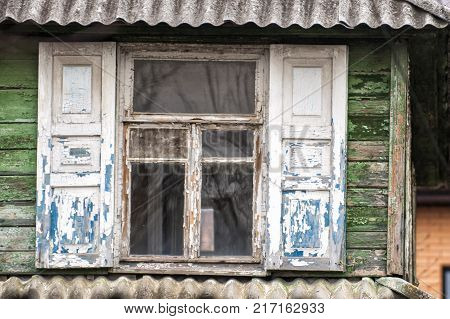 simple white window with shutters on a green wooden wall