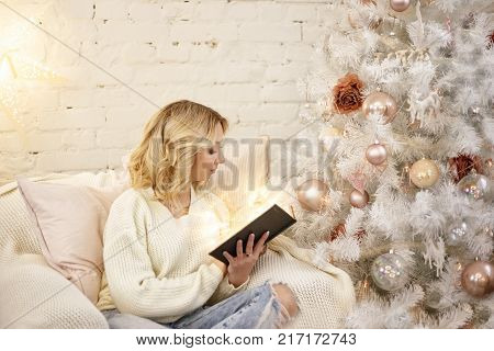 beautiful woman reading a book at the Christmas tree