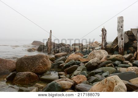 Wet rocks and old wooden posts at the bay of Atlantic Ocean