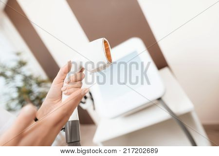 Close up. A female doctor holds a device for laser hair removal. It shows the working area of the device. On the background of a modern beauty salon.