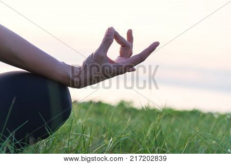 Close up of hand in a meditation pose . Woman exercising vital and meditation for fitness lifestyle in the beach sunset background. Healthy Concept