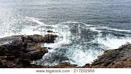 Coast of the Spanish atlantic ocean in La Coruna. Sea breaking against the rocks of a cliff