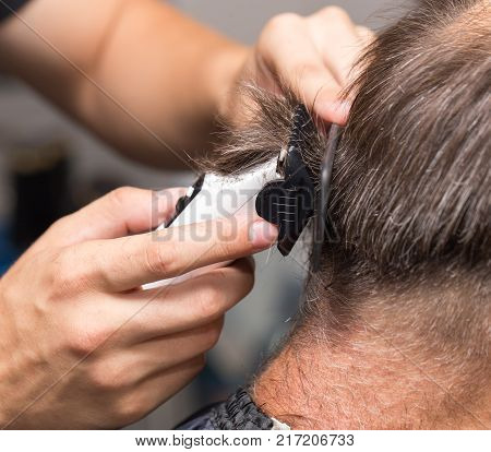 Close up of a male student having a haircut with hair clippers .
