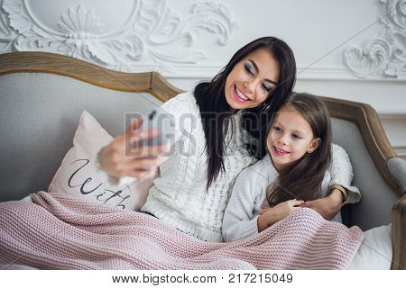 Well-groomed hand of a woman holding a phone taking a selfie with her daughter, little girl.