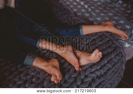 Feet in bed. Couple man and girl lying in clothes pants blue on the bed, legs touching each other