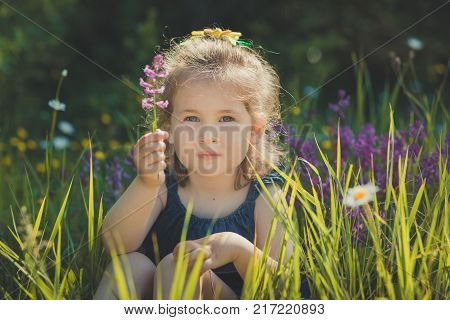 Cute Blond Young Girl Child Stylish Dressed In Blue Jeans Dress Posing On Meadow Of Forest Wild Mayw