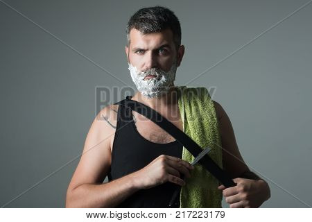 Fashion and beauty innovation. Barber and hairdresser. Serious hipster in barbershop new technology. Haircut of bearded man archaism. Man cut beard and mustache with razor and shaving brush.
