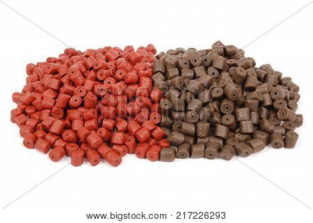 Brown with red pre-drilled halibut pellets for carp fishing isolated on white background with soft shadow
